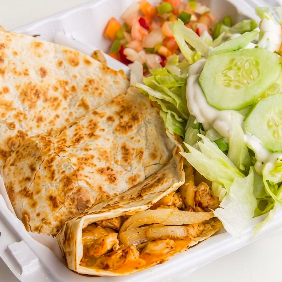 Grilled stuffed flatbreads with chicken and vegetables served alongside lettuce, cucumber, tomato, and salad in a takeaway container.